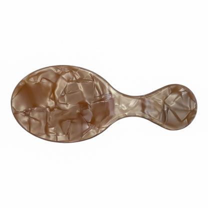 Mini oval hair brush with a marbled light brown pearl finish and curved handle, perfect for personalization and on-the-go touch-ups.

