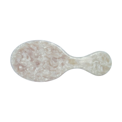 Top view of a mini travel hairbrush with a pearl-textured ivory handle, designed for compact styling and on-the-go touch-ups.